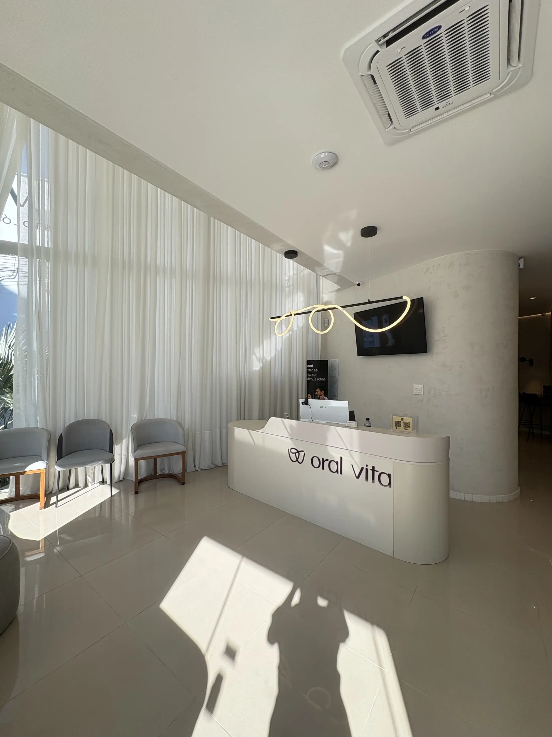 Recepção da Oral Vita em Itajaí, com luz natural e o logotipo retroiluminado